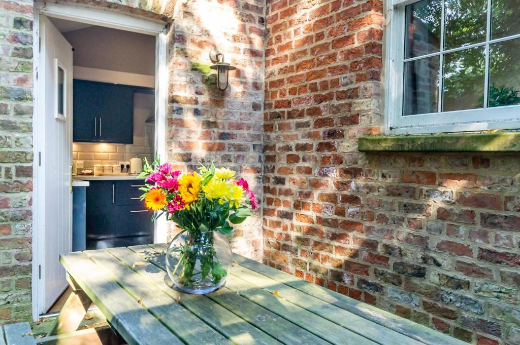 een vaas met bloemen op een houten tafel bij Middlethorpe Manor - No1 Relax and Unwind in York