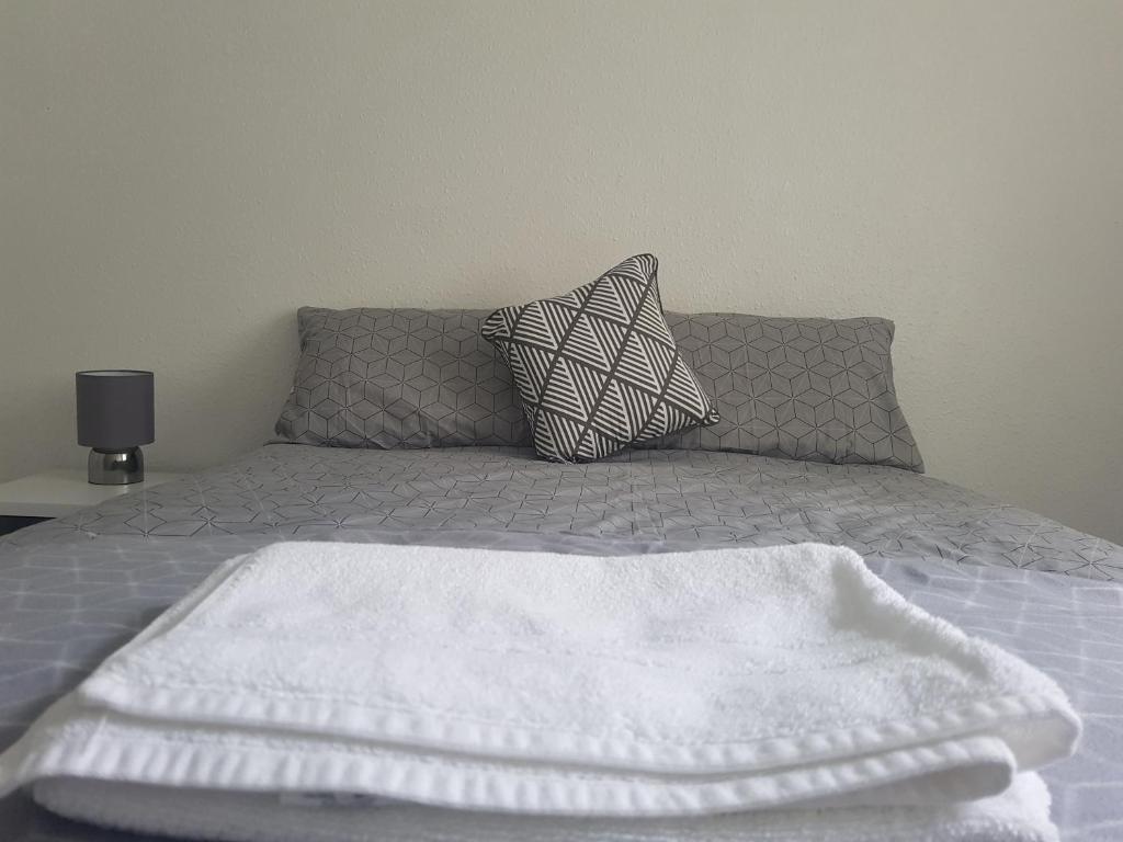Una cama con una manta blanca y almohadas. en Cosy Room in Galashiels en Galashiels
