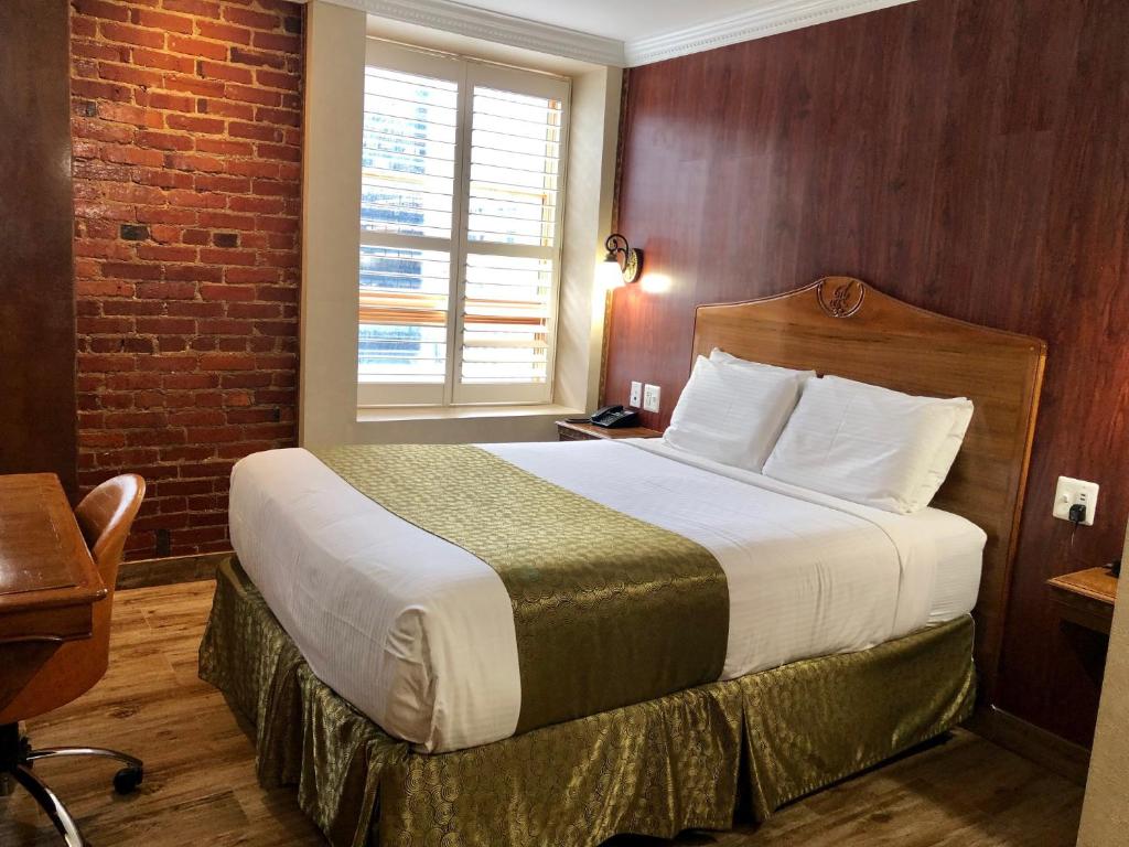 ワシントンにあるジ アーキテクトのレンガの壁のベッドが備わるホテルルームです。