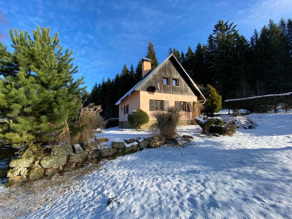 ein Haus im Schnee mit einer Steinmauer in der Unterkunft Chata Maxík in Josefův Důl u Jablonce nad Nisou