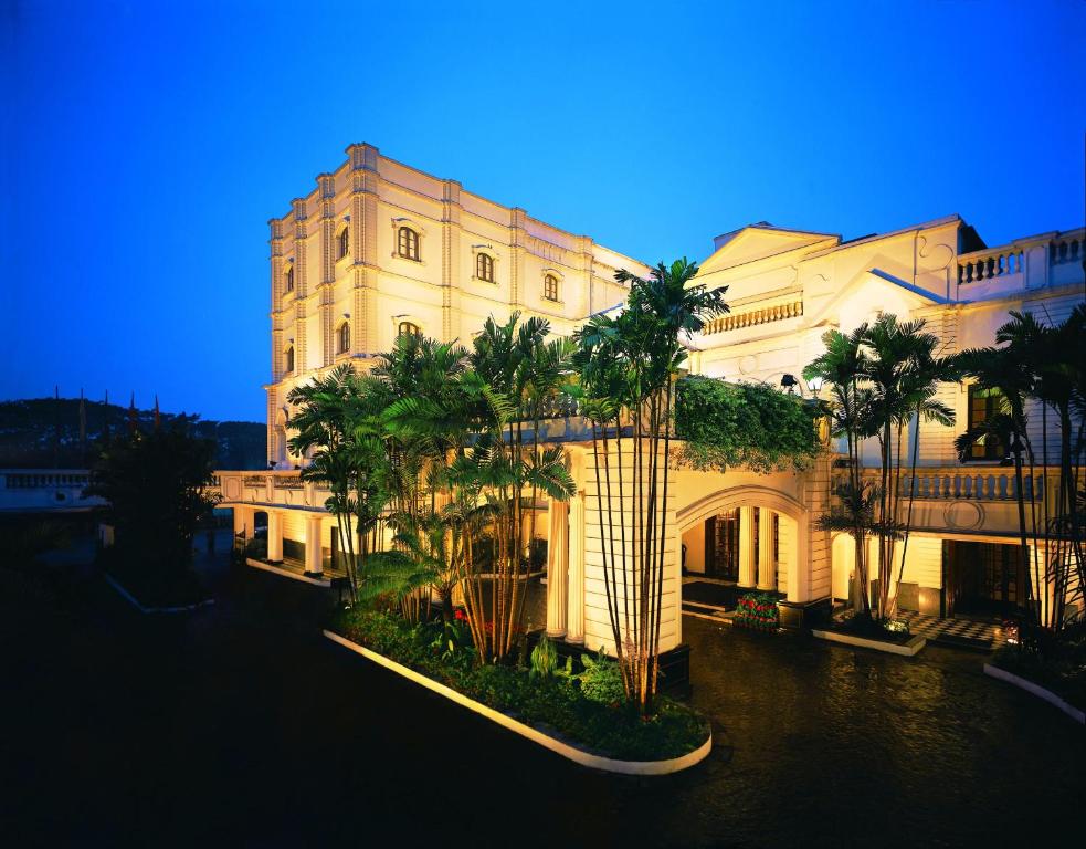 a large building with palm trees in front of it at The Oberoi Grand Kolkata in Kolkata