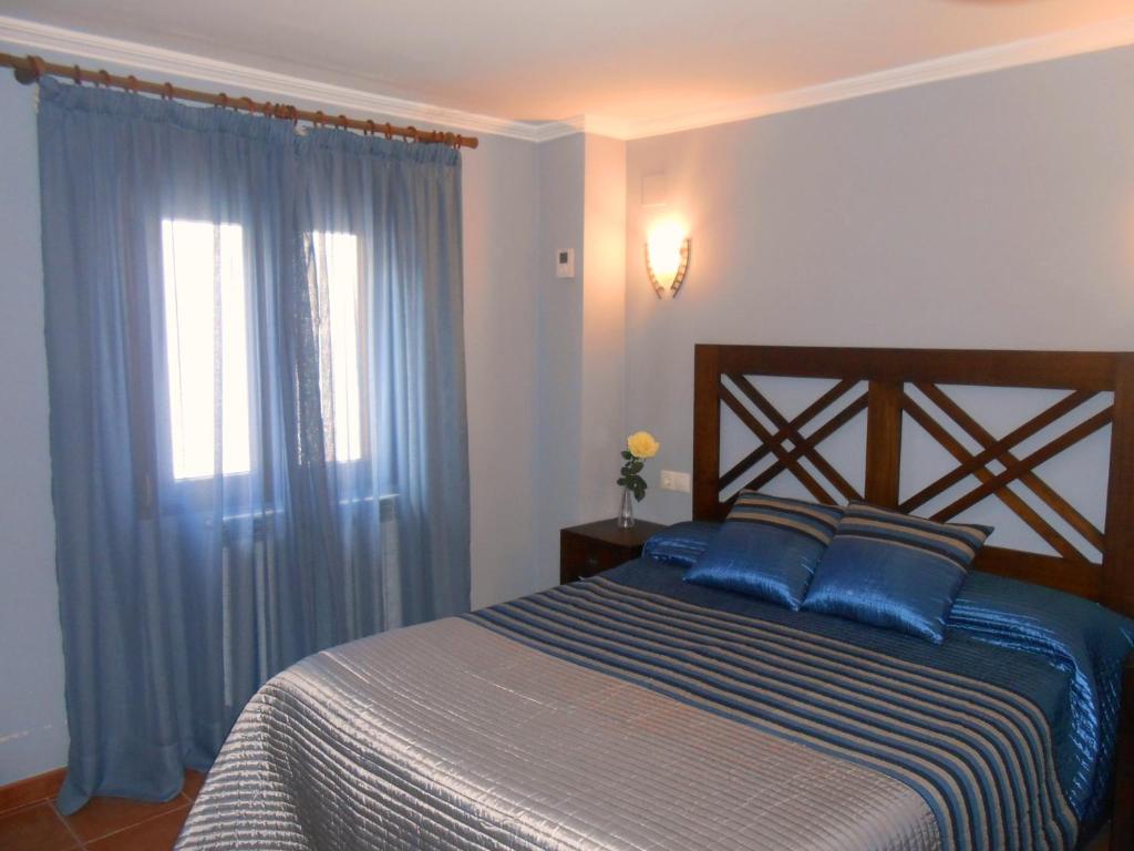 a bedroom with a bed with blue pillows and a window at Casa Navarrete in El Cuervo