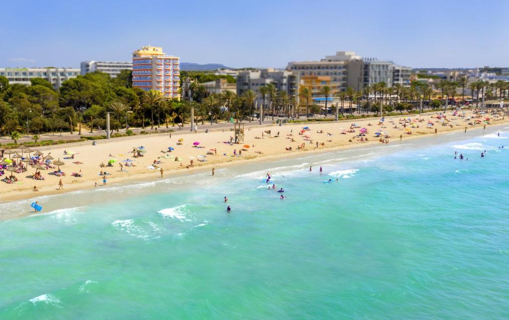 a beach with a bunch of people in the water at Leman Hotel y Apartamentos in Playa de Palma