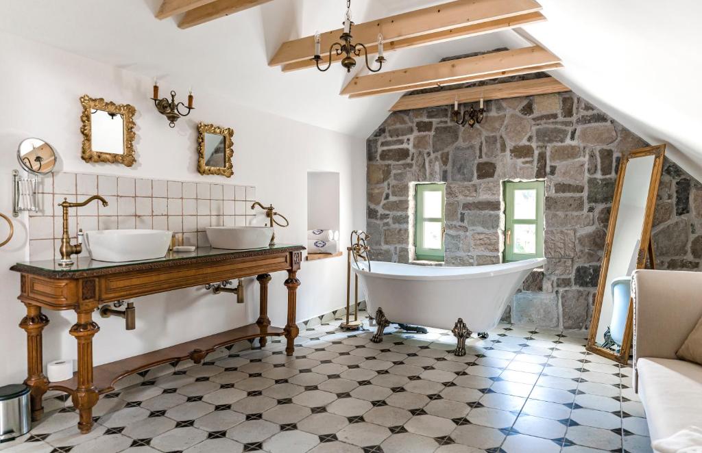 a bathroom with a tub and a stone wall at Hazai Provence in Kapolcs