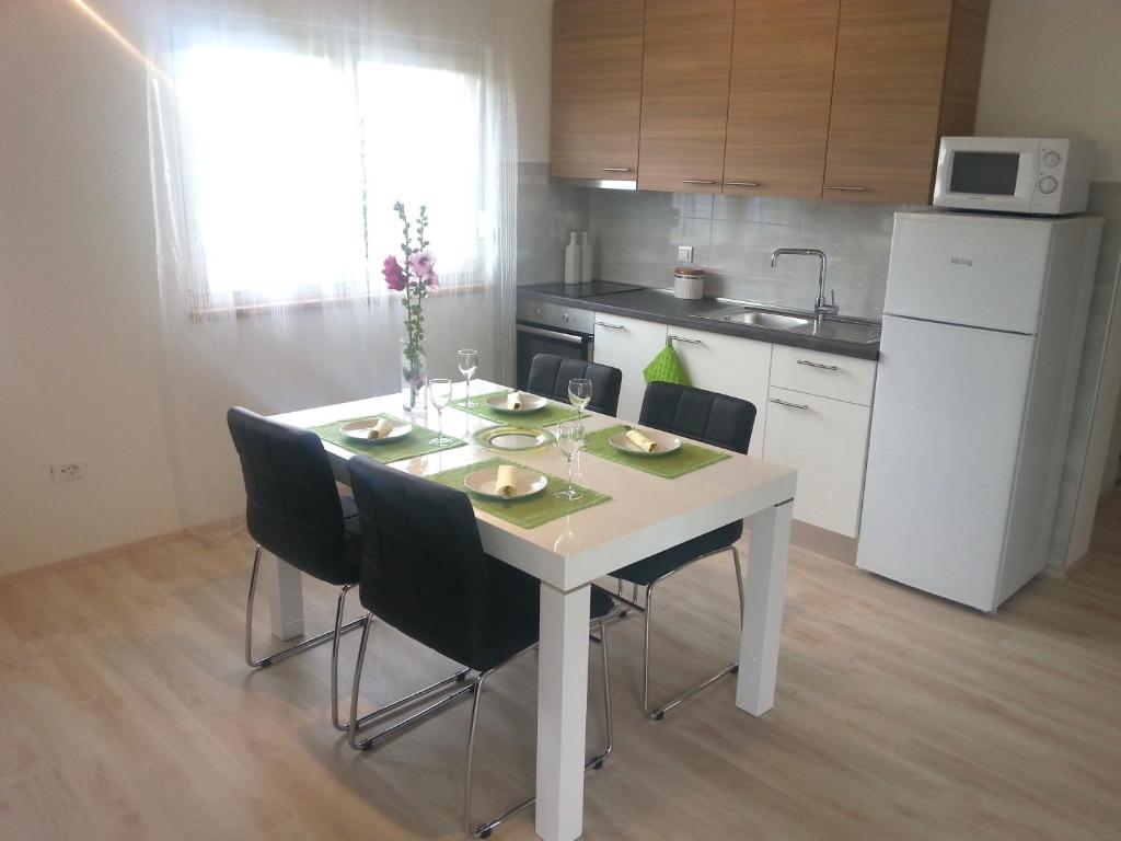 cocina con mesa blanca con sillas y nevera blanca en Apartments Levanat, en Zadar