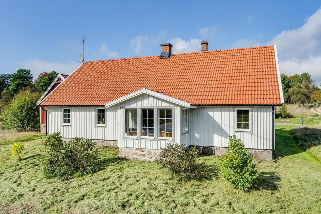 uma pequena casa branca com um telhado laranja em Spacious and newly renovated farmhouse with indoor pool em Knäred