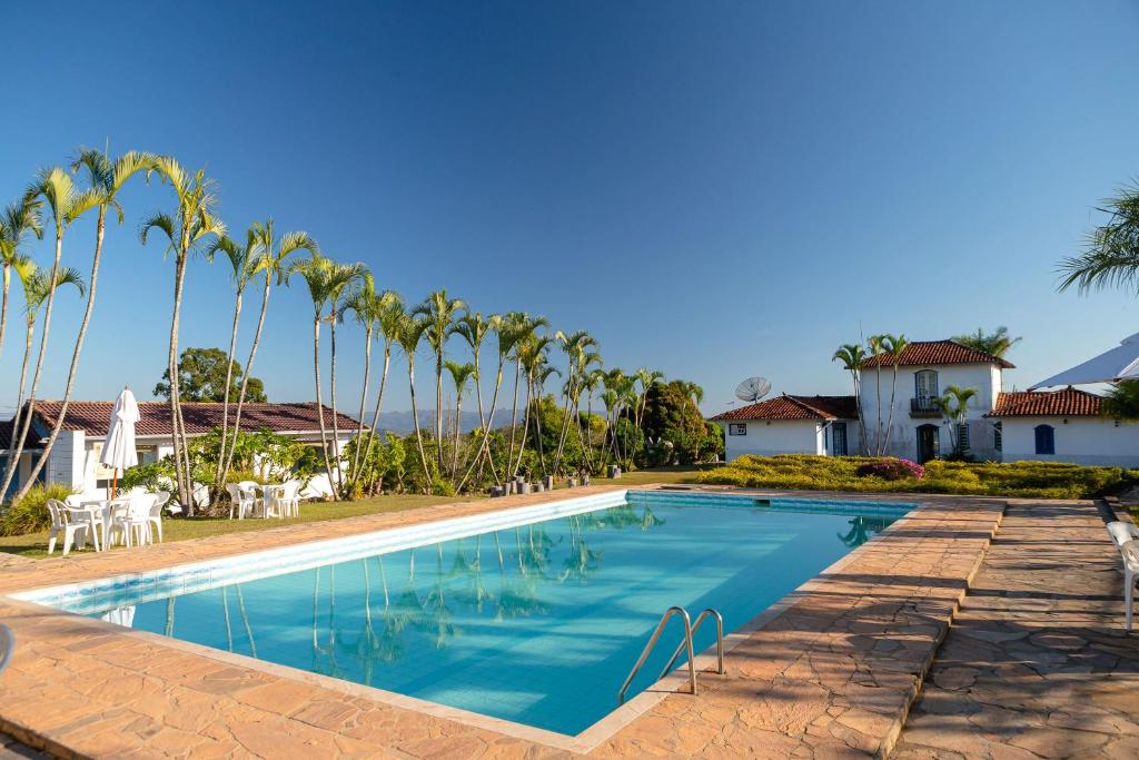 uma piscina em frente a uma casa com palmeiras em VOA Mirante Do Café em Santo Antônio do Leite