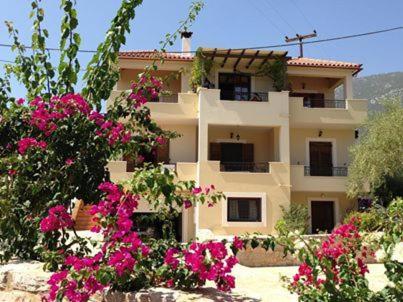 un edificio con flores rosas delante de él en Alexandraki Rooms, en Poulithra