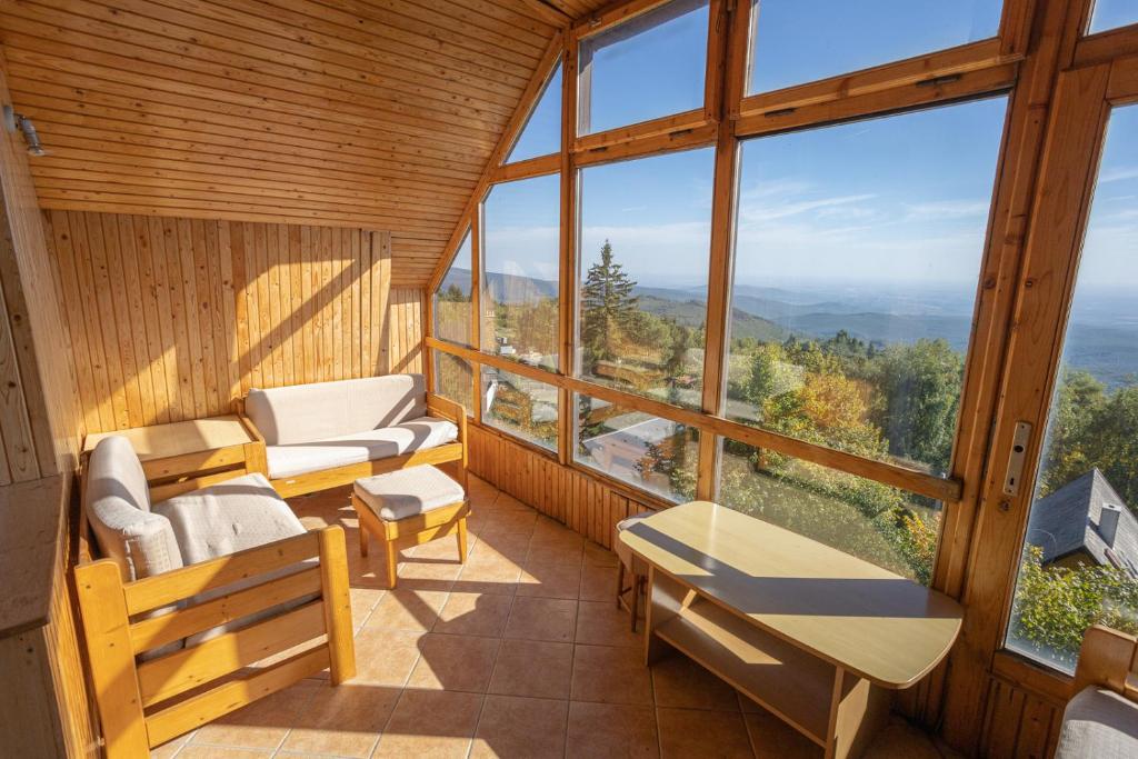 Zimmer mit einem Balkon mit Stühlen, Tischen und Fenstern in der Unterkunft Mátra Sasfészek in Mátraszentimre