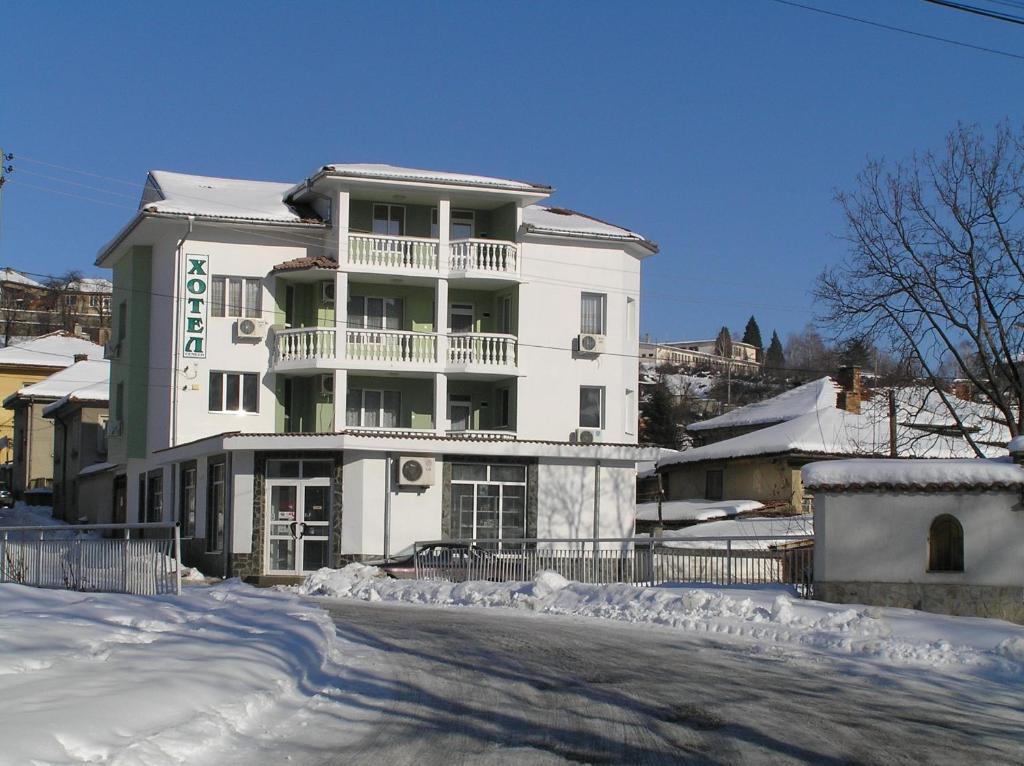 a white building with a balcony in the snow at Karadzhovy Guest House in Kalofer