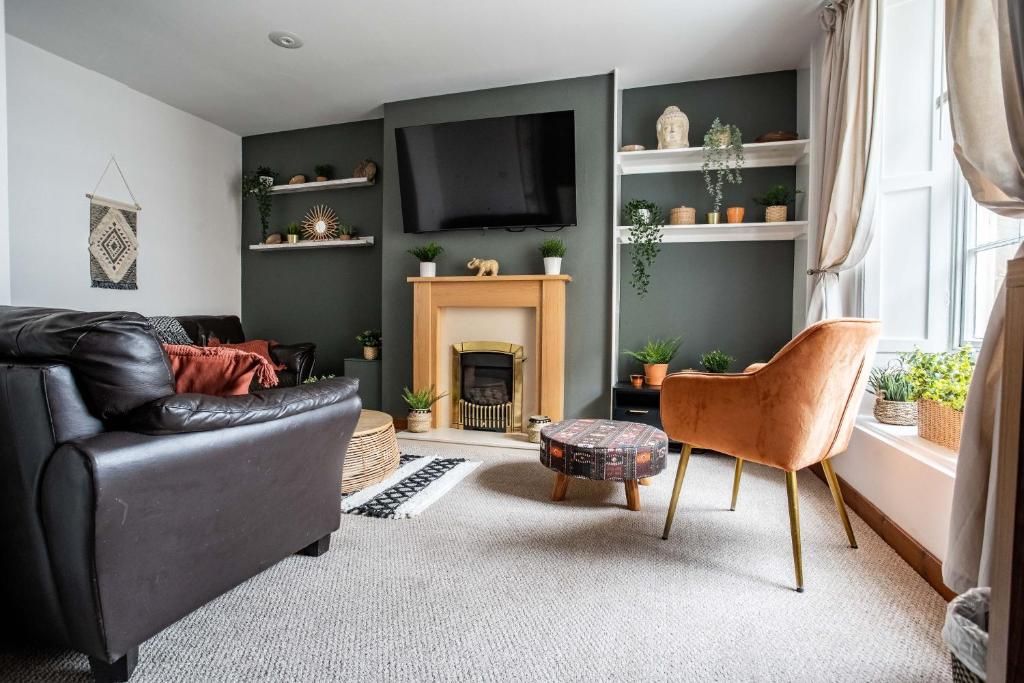 a living room with a black leather couch and a fireplace at The Bottles Lodge in Alnwick