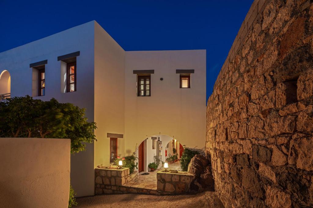 a house with white walls and a stone wall at Iliolousto Studios in Skala