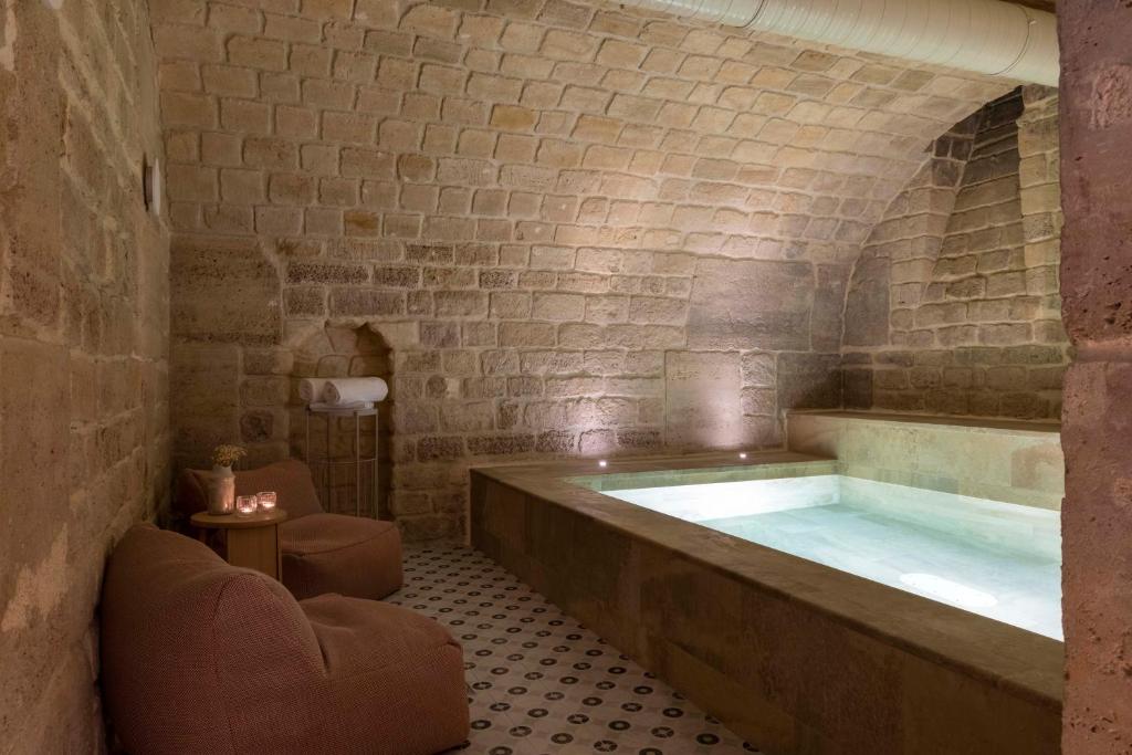 a bathroom with a large tub in a brick wall at Le Petit Beaumarchais Hotel & Spa in Paris