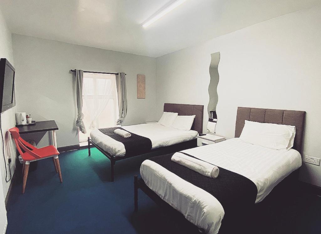 um quarto de hotel com duas camas e uma cadeira vermelha em Kings Hotel Blackburn em Blackburn