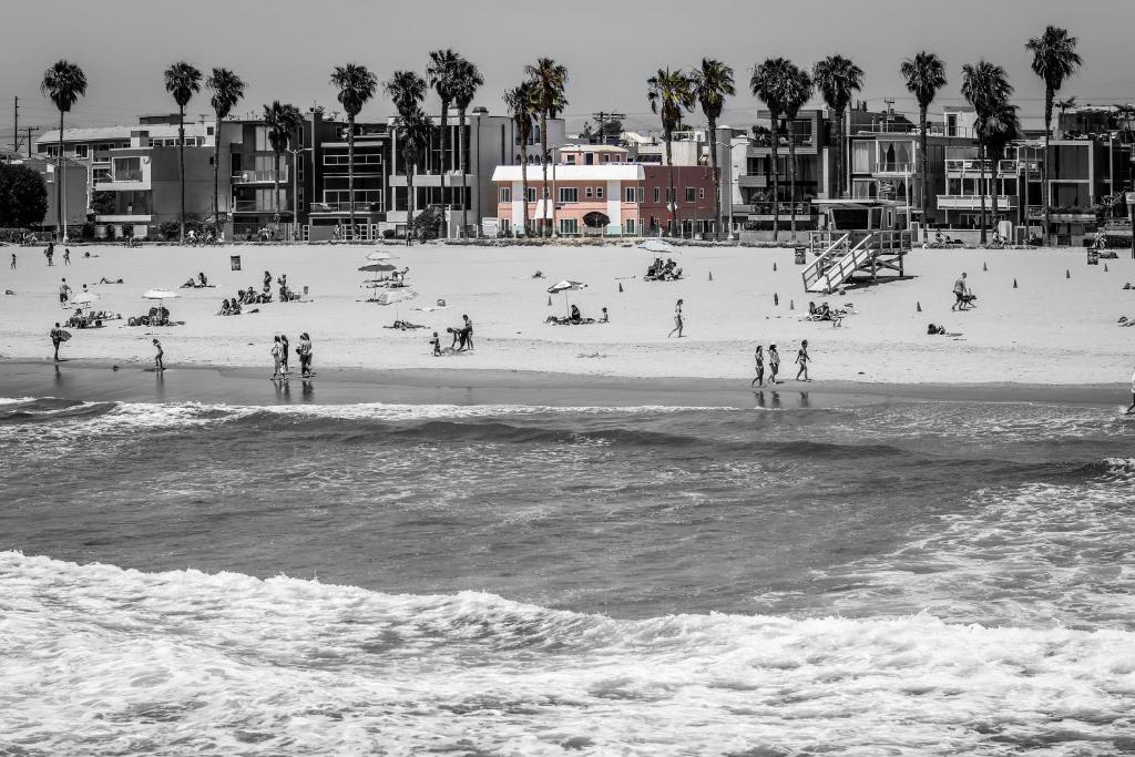 a black and white photo of a beach with people at Venice on the Beach Hotel in Los Angeles