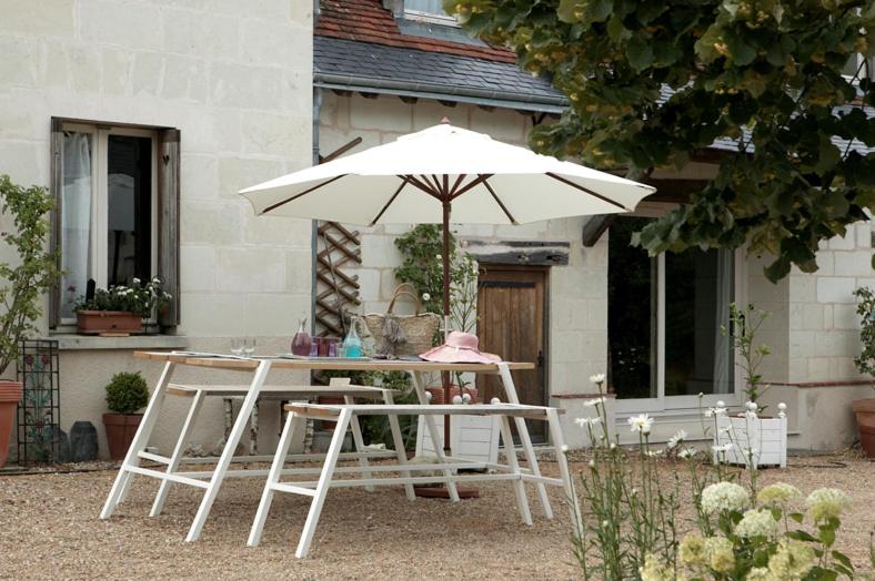 una mesa blanca y sillas con sombrilla en Une Maison, Un Jardin, en Berthenay