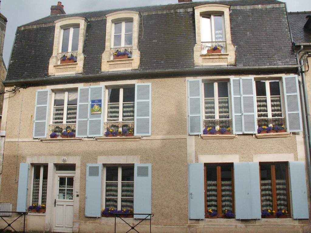 a building with white shutters and flowers on the windows at Chambre d&#39;hôtes - Dodo et tartines in Bayeux