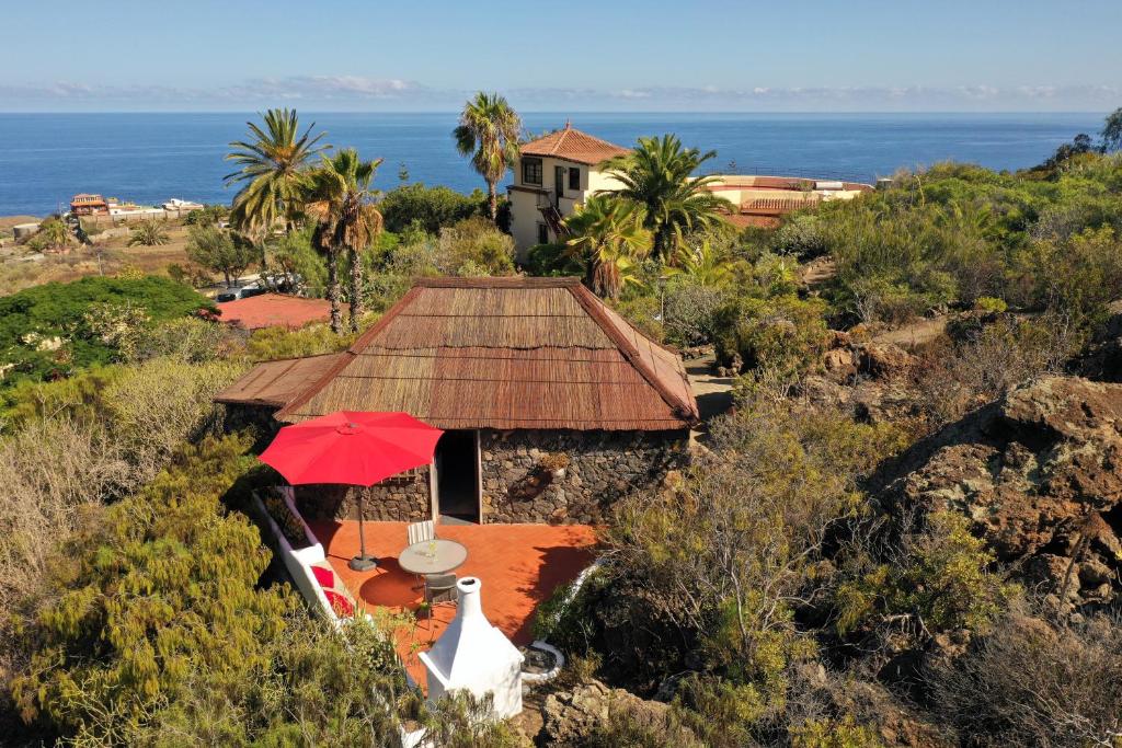una casa con una sombrilla roja junto al océano en Pajar - Finca Tabaiba By TOR, en Icod de los Vinos