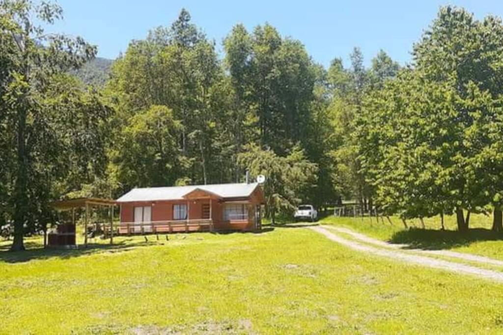 uma cabana no meio de um campo com uma estrada em Cabañas simple Pucon em Pucón