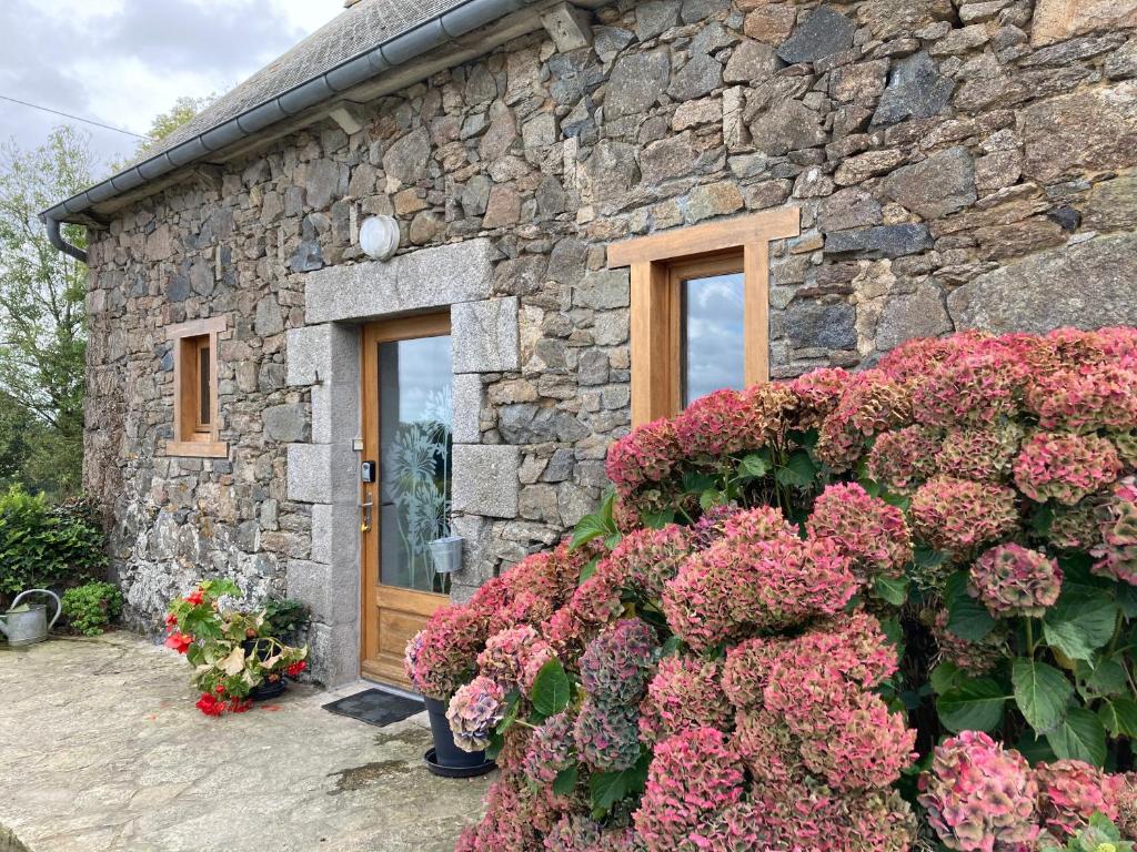 a stone house with pink flowers in front of it at Petite maison de campagne in Plouëc-du-Trieux