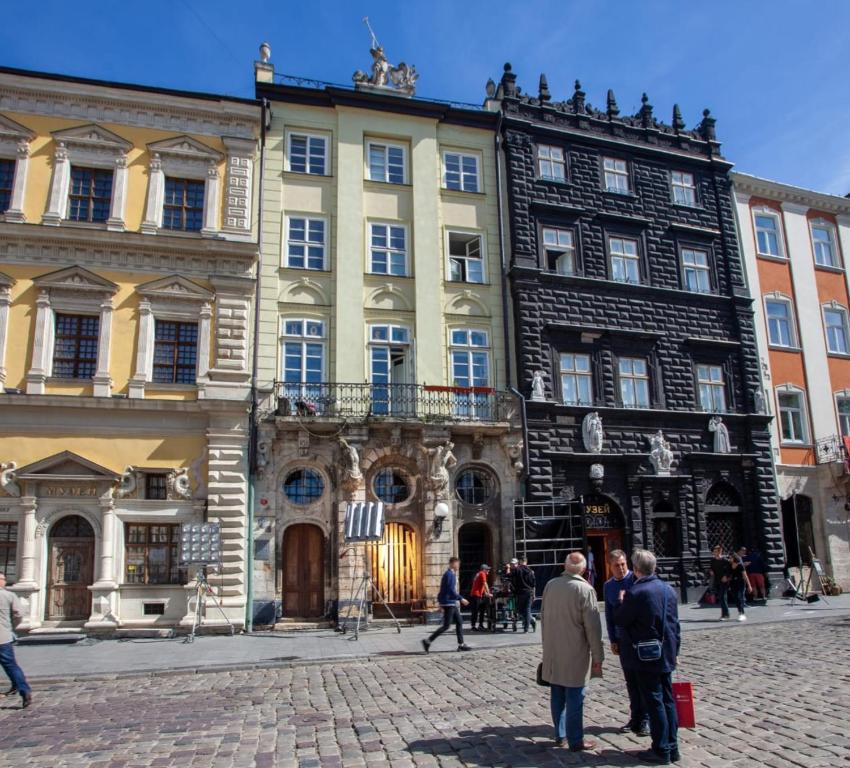 a group of people standing in front of a building at ARTrooms -round windows Rynok Sq in Lviv