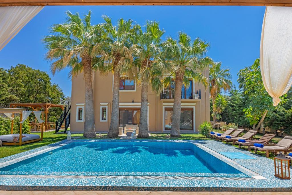 a pool with palm trees in front of a house at Luxury Mansion Rhodes in Ialysos