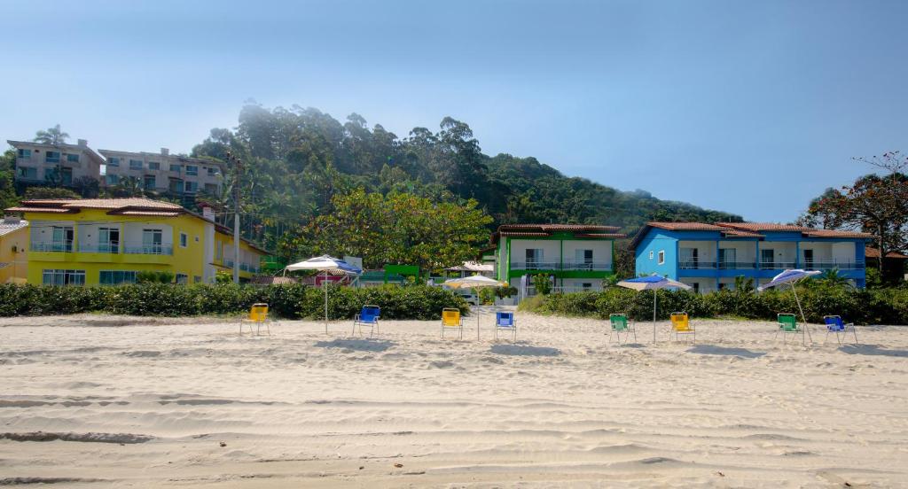 a beach with chairs and umbrellas in the sand at Pousada Canto das Pedras in Bombinhas