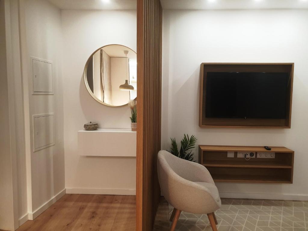 a living room with a television and a chair at Green Garden Houses in Chaves