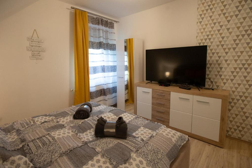 een slaapkamer met een bed en een flatscreen-tv bij Égerliget Vendégház in Harkány