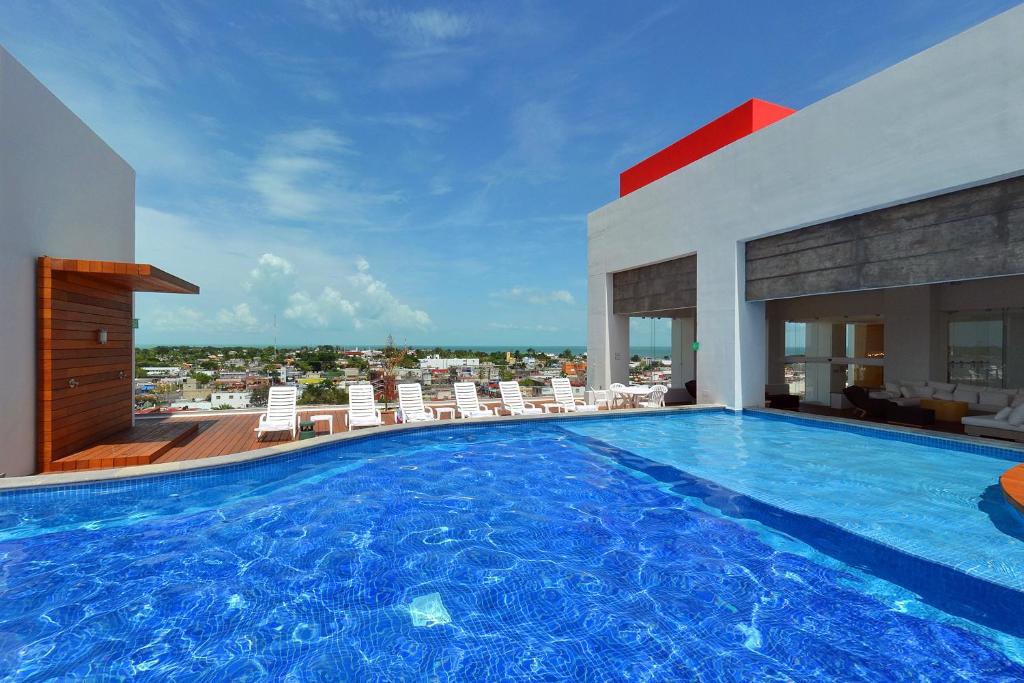uma grande piscina com cadeiras e um edifício em Fiesta Inn Chetumal em Chetumal