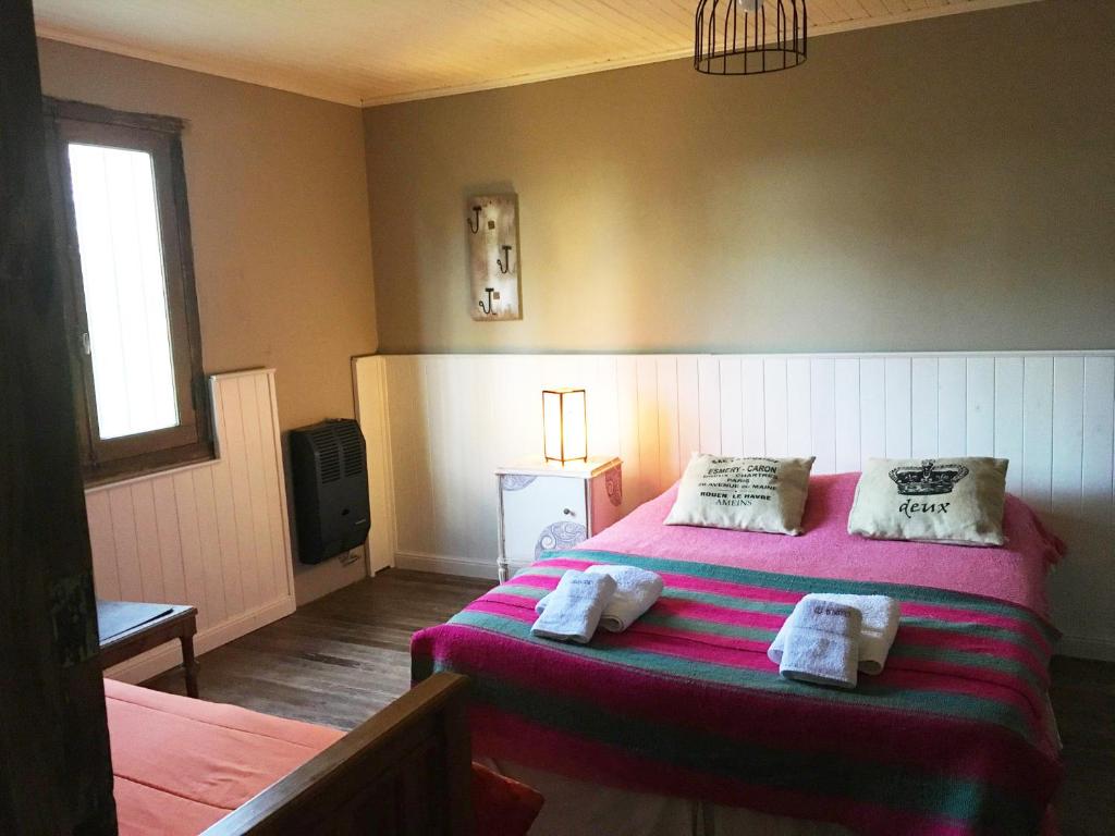 a bedroom with a pink bed with towels on it at Casa de Campo La Colorada in Las Flores