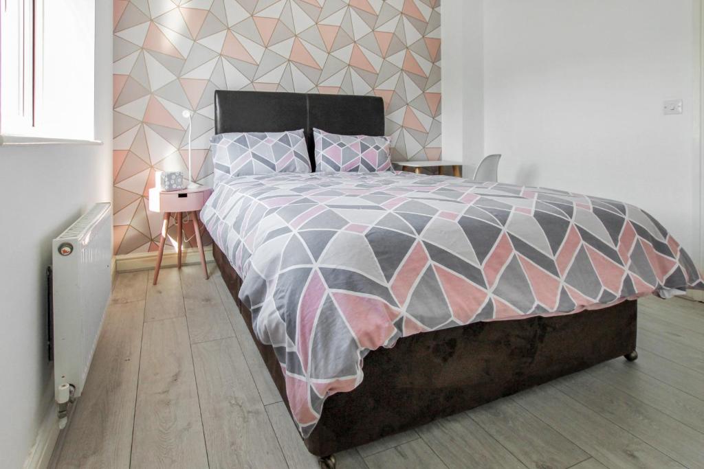 1 dormitorio con 1 cama con edredón rosa y gris en Pink Sapphire Double Room with En-suite & Wifi en Derby