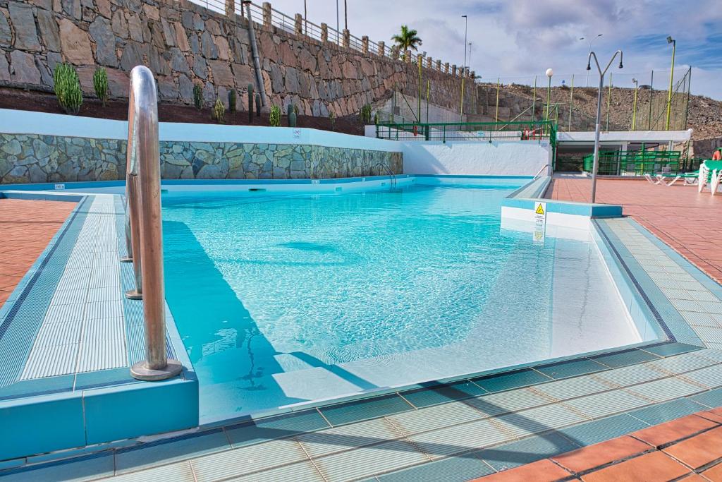une grande piscine avec un poteau en bois dans l'eau dans l'établissement Malibu 2 apartamento con aire acondicionado, campo de tennis y piscina con solarium, à Puerto Rico
