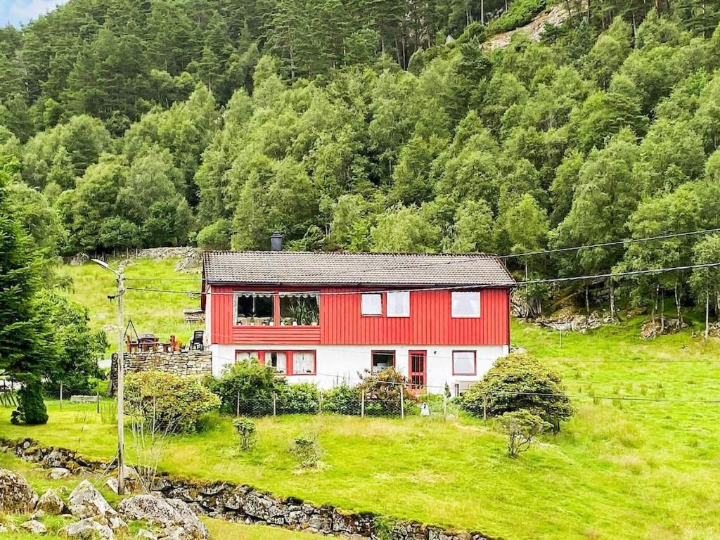 una casa roja y blanca en una colina con árboles en Apartment Reksteren, en Haukafer