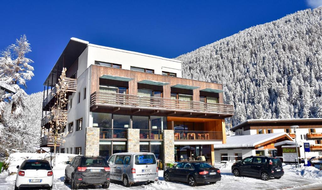 ein Gebäude mit Autos, die draußen im Schnee geparkt sind in der Unterkunft Bed & Breakfast Hotel Nives in Sulden