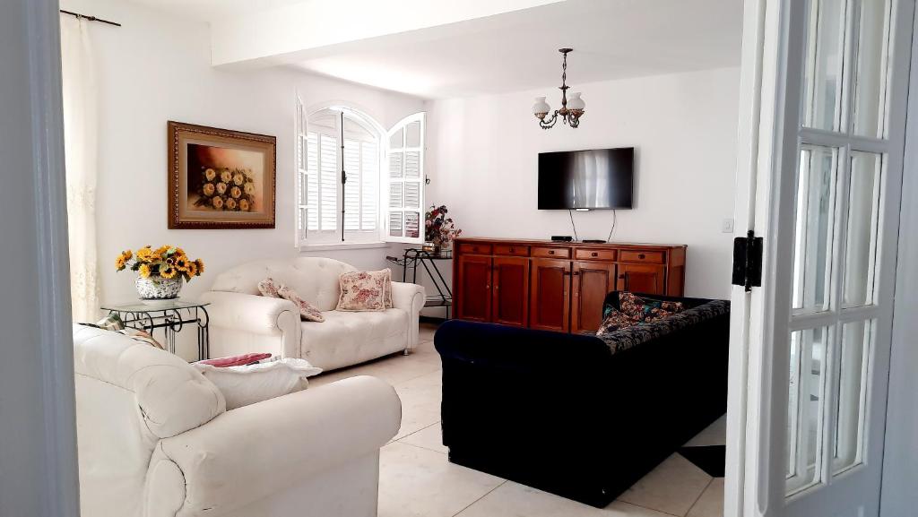 a living room with two white couches and a tv at Dikasa Alugue Temporada in Ouro Preto