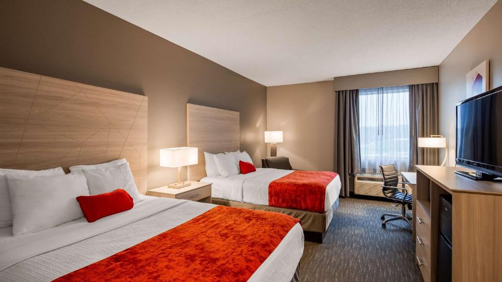 a hotel room with two beds and a flat screen tv at Best Western Plus New Cumberland in New Cumberland