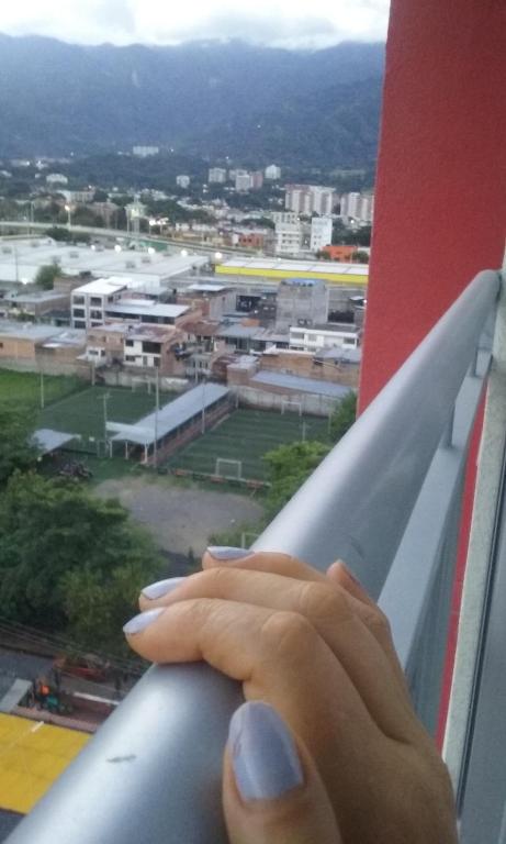 a hand on a window ledge looking out at a city at Habitación Privada in Ibagué