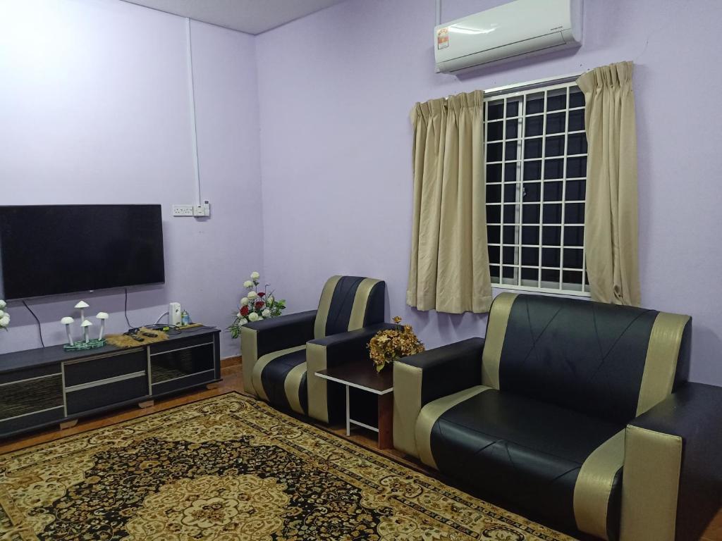 a living room with two chairs and a flat screen tv at Aliza Scawa Homestay in Kuala Pilah