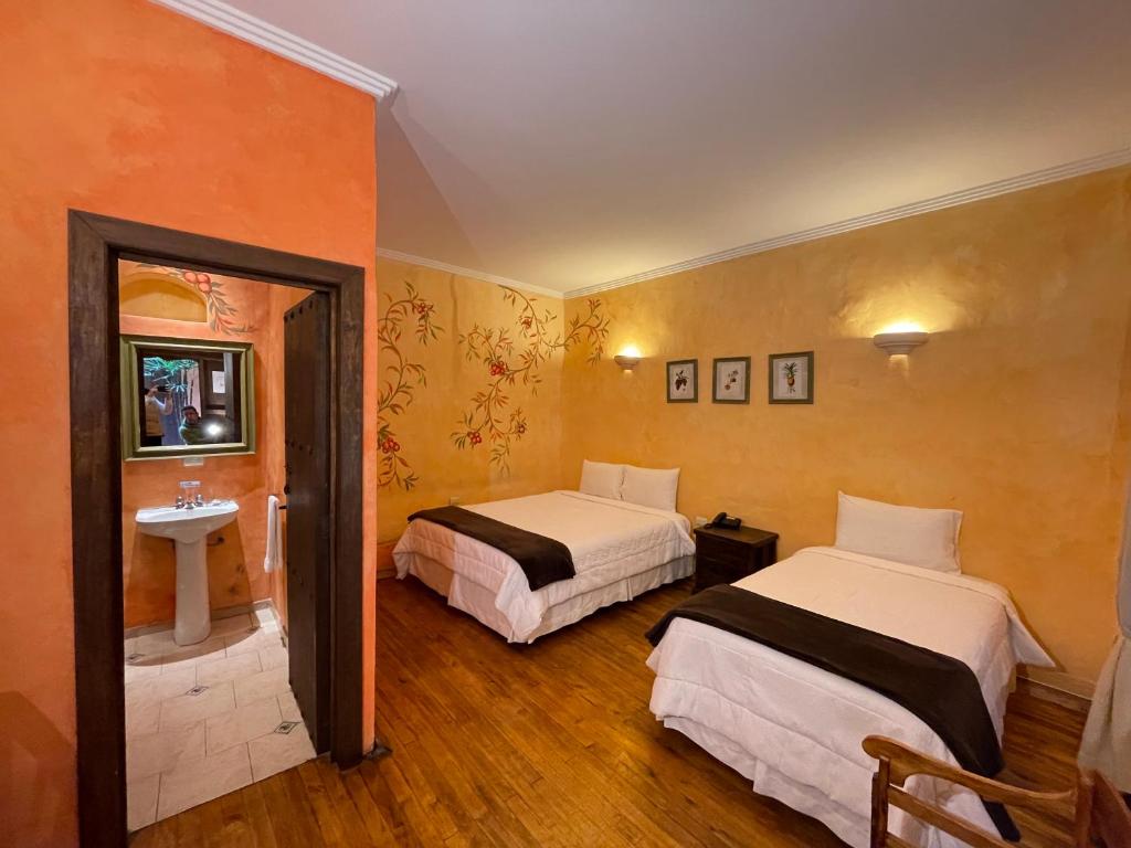 a hotel room with two beds and a sink at NASS Casa del Aguila in Cuenca