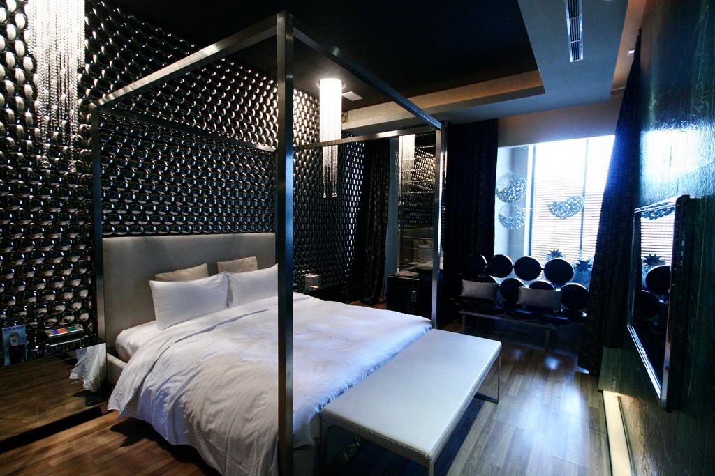 The Yorker Deluxe Motel في تاويوان: غرفة نوم بها سرير مظلة مع مقعد وكراسي