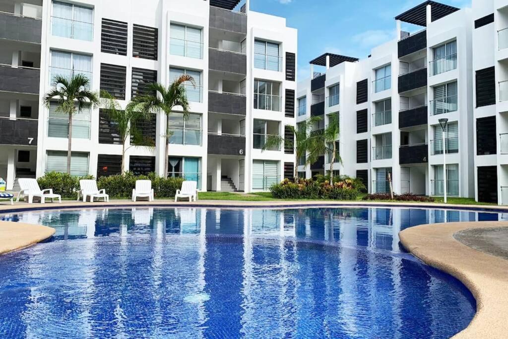 a swimming pool in front of a building at Hermoso departamento con alberca in Manzanillo