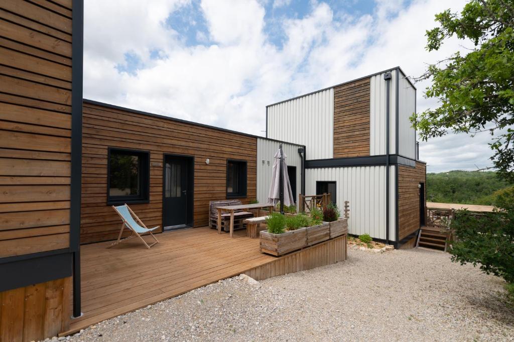 a house with a wooden deck with a patio at Lot en Dock 3 logements atypiques et écologiques en vallée de la Dordogne in Souillac