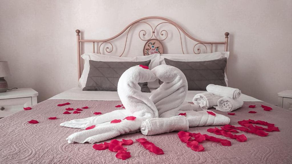 Dos cisnes hechos de toallas en una cama con rosas en "B&B La Lanterna" Trulli & Dimore Storiche, en Alberobello