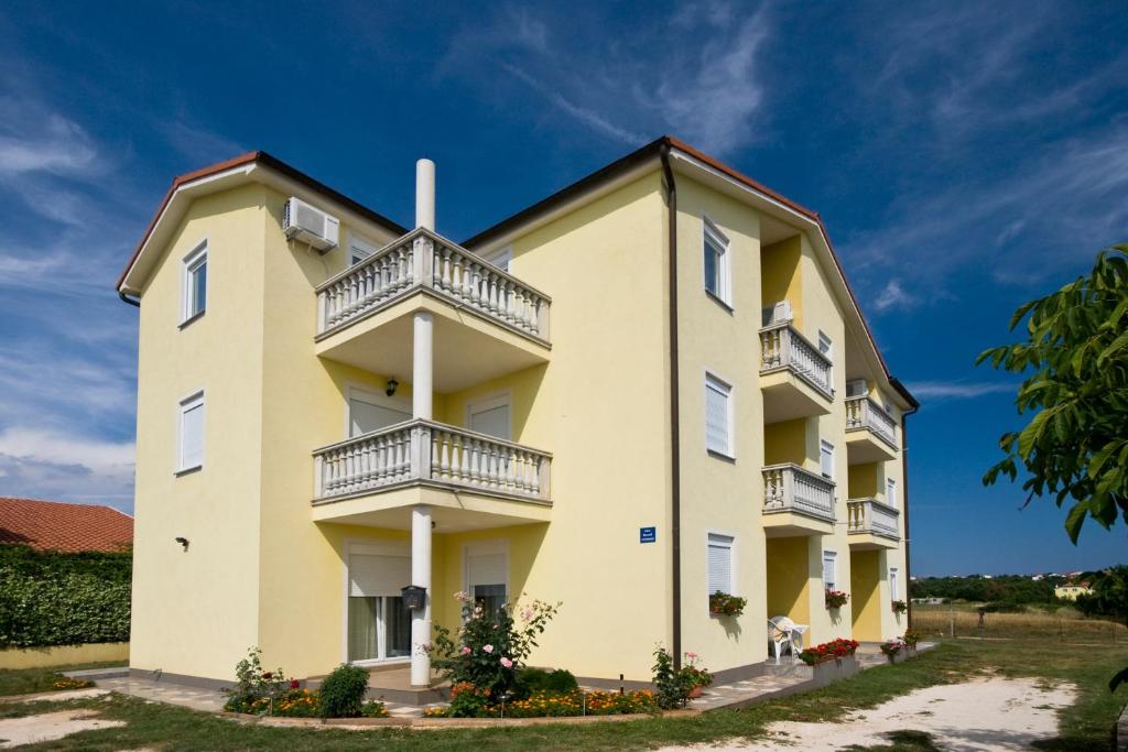 ein großes gelbes Gebäude mit Balkonen darauf in der Unterkunft Apartments Baresic in Medulin