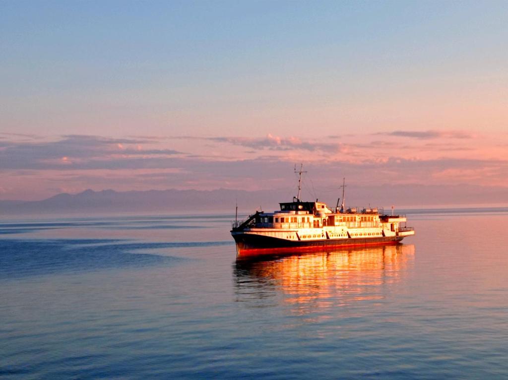リストヴャンカにあるApartments on the Baikalの夕日の水上に座る船
