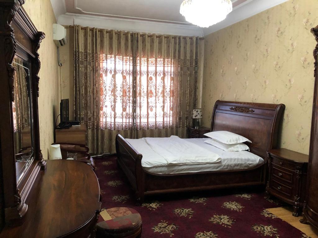 a bedroom with a bed and a table and a window at Hello Dushanbe Guest House in Dushanbe