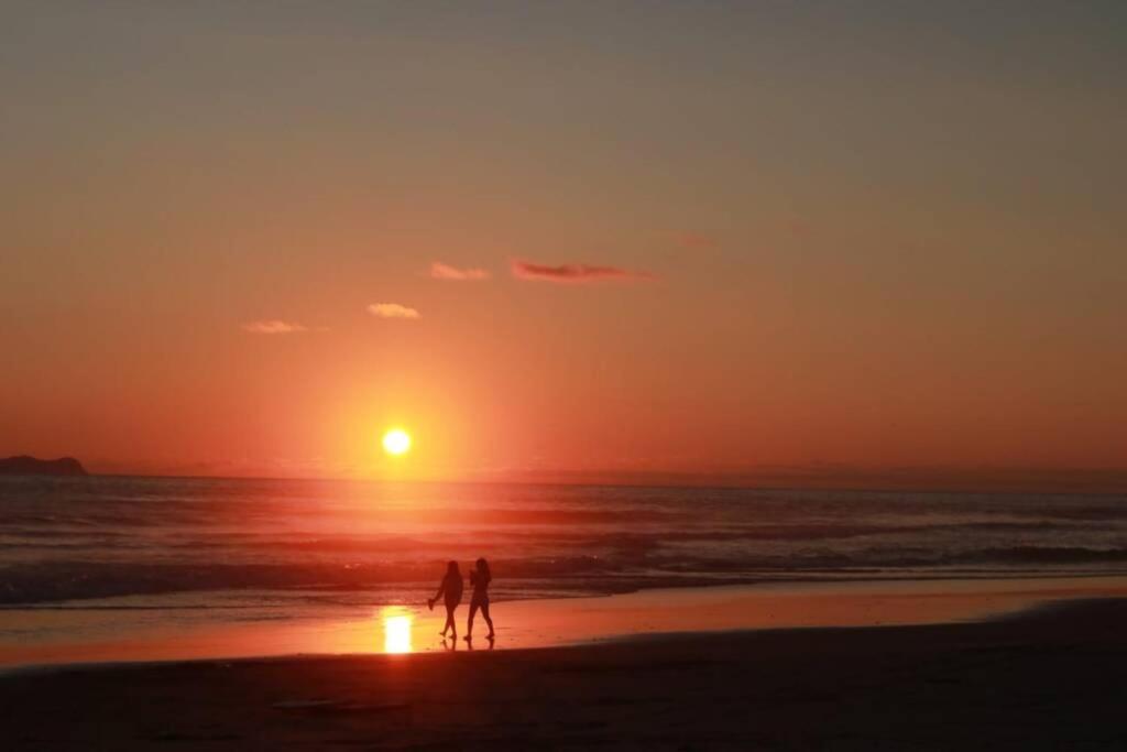 Dos personas caminando por la playa al atardecer en Paraíso en Rosarito a pie de la playa, en Rosarito