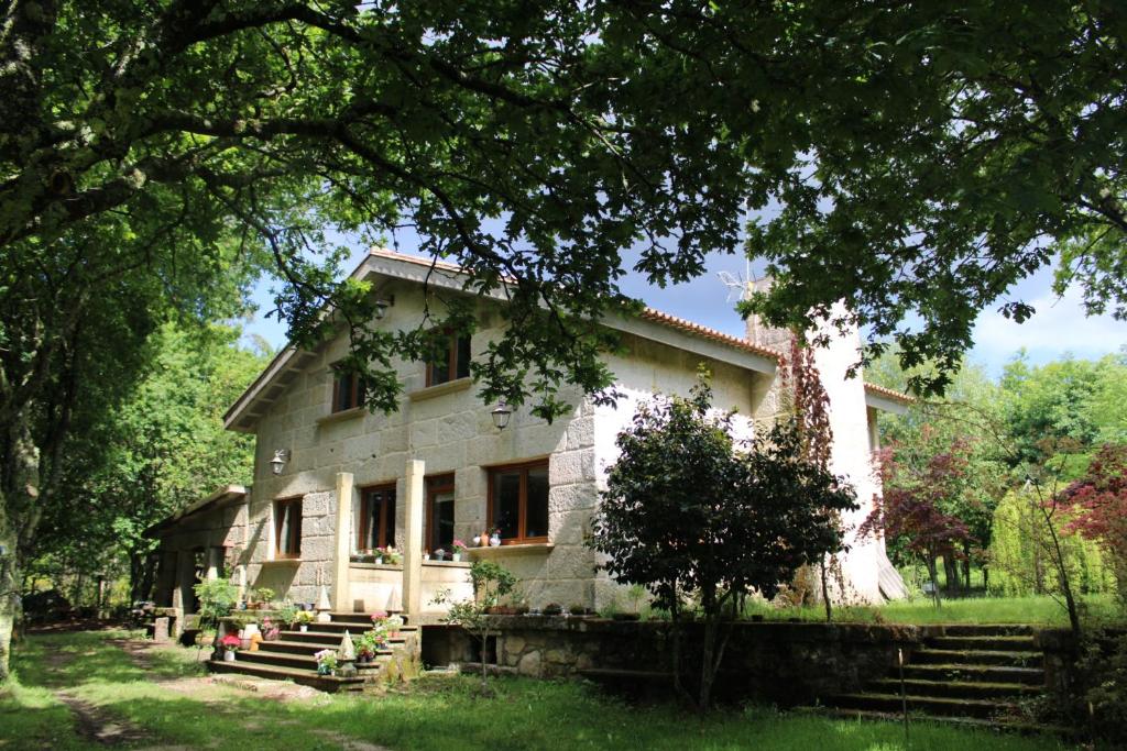 Una casa blanca con un árbol delante. en Villa Casa de Campo Los Carballos, en Tomiño