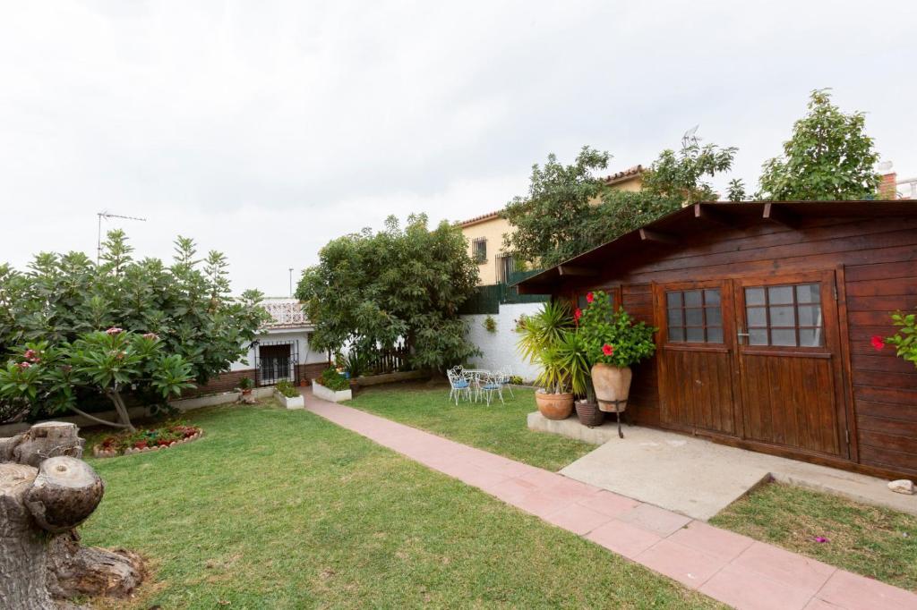 a backyard of a house with a wooden garage at Bonito chalet en La Cala con gran jardín privado in Cala del Moral